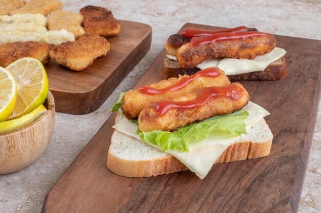 Salsiccia alla griglia e bocconcini di pollo su toast con erbe e spezie su un piatto di legno.