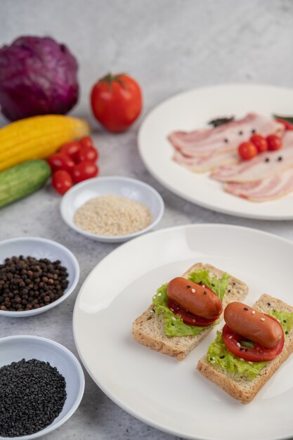 Salsiccia con pomodori, insalata e due set di pane su un piatto bianco.