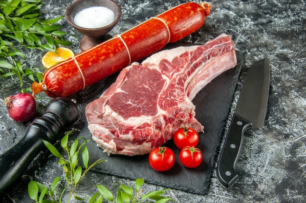 Salsiccia fresca a metà vista con pomodori e fetta di carne su superficie scura chiara