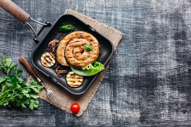 Salsiccie a spirale grigliate saporite per il pasto su fondo di legno grigio