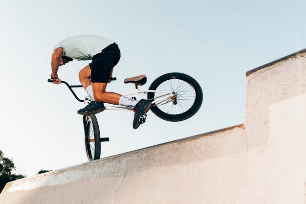 Salto estremo dell'uomo sportivo con la bicicletta