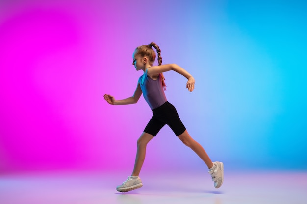 Salutare. Ragazza adolescente, corridore professionista, pareggiatore in azione, movimento isolato su sfondo rosa-blu sfumato in luce al neon. Concetto di sport, movimento, energia e stile di vita dinamico e sano.