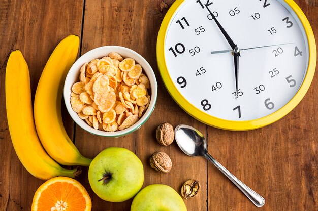 Sana colazione fatta in casa di muesli, mele, frutta fresca e noci con orologio