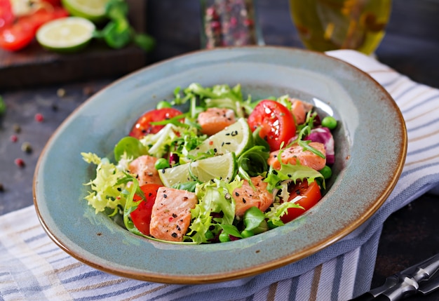 Sana insalata con pesce. Salmone al forno, pomodori, lime e lattuga. Cena salutare.