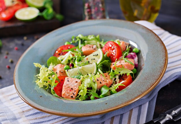 Sana insalata con pesce. Salmone al forno, pomodori, lime e lattuga. Cena salutare.