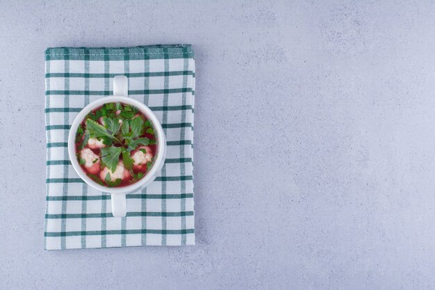 Sana porzione di zuppa di cavolfiore in una piccola ciotola su tovaglia piegata su sfondo marmo. Foto di alta qualità