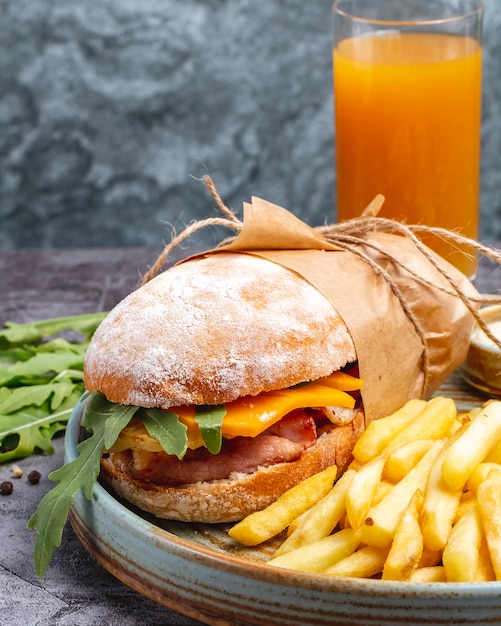 Sandwich di pollo con formaggio cheddar e rucola servito con succo d'arancia di patatine fritte