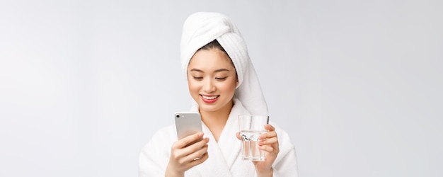 Sano giovane bella donna acqua potabile bellezza viso trucco naturale con azienda telefono cellulare isolato su sfondo bianco