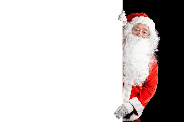 Santa Claus felice che tiene il fondo in bianco dell&#39;insegna della pubblicità con lo spazio della copia. Babbo Natale sorridente che indica nel segno in bianco bianco. Tema natalizio, vendite