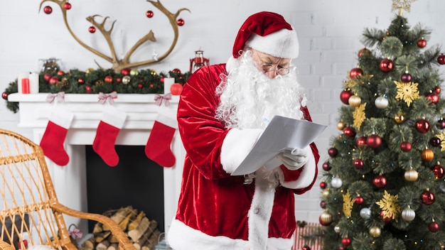 Santa in piedi vicino all&#39;albero di Natale decorato