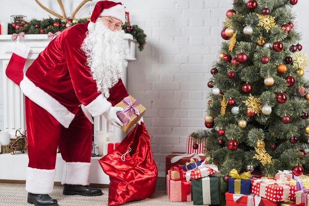 Santa mettendo regali sotto l&#39;albero di Natale