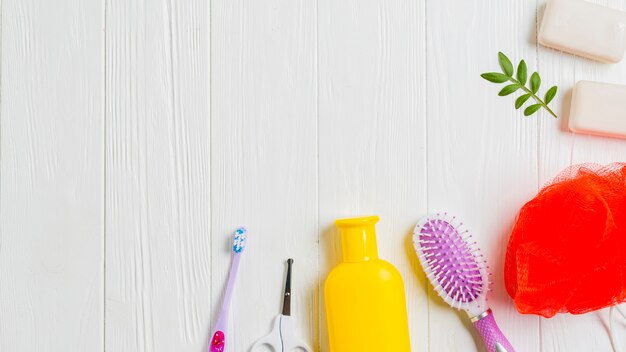 Sapone; spazzolino da denti; forbice; spazzola per capelli e spugna su fondo in legno