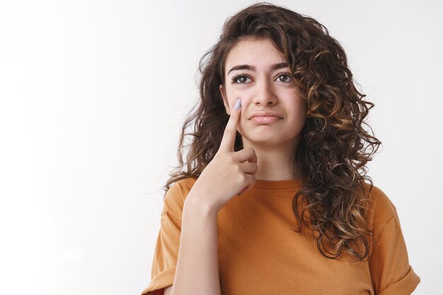 Sarcastica ragazza armena dai capelli ricci carina tenere la macchina fotografica del dito indice come mostrare la lacrima che agisce sconvolto sentirsi rimpianto tristezza in piedi infastidito cattivi pensieri, piagnucolando lamentando vita sfortunata