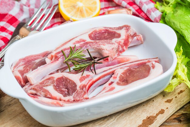 Scaglie di agnello crudo con spezie e erbe close-up su sfondo di legno