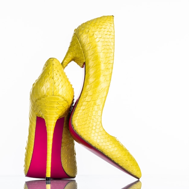 Scarpa tacco alto della donna alla moda isolata su priorità bassa bianca. Bello pattino femminile giallo dei tacchi alti. Lusso. Retrovisore