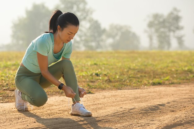 Scarpe da corsa runner donna che lega i lacci per l'autunno eseguito nel parco forestale corridore che prova le scarpe da corsa che si preparano per la corsa. Jogging ragazza esercizio motivazione salute e fitness.