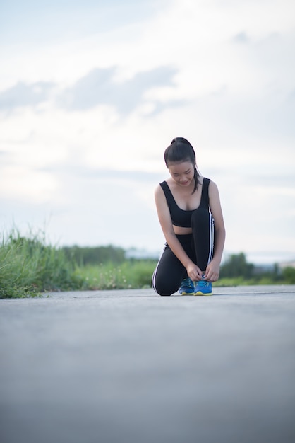 Scarpe da vicino Corridore femminile che lega le sue scarpe per un esercizio di jogging