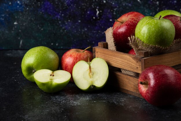 Scatola di legno di mele biologiche fresche su superficie nera. .