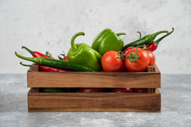 Scatola di legno piena di verdure fresche su marmo.