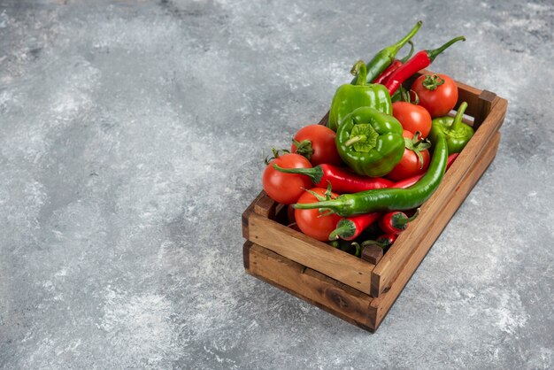 Scatola di legno piena di verdure fresche su marmo.