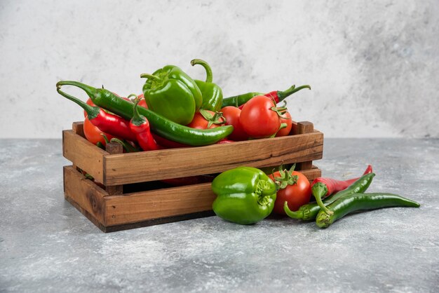 Scatola di legno piena di verdure fresche su marmo.