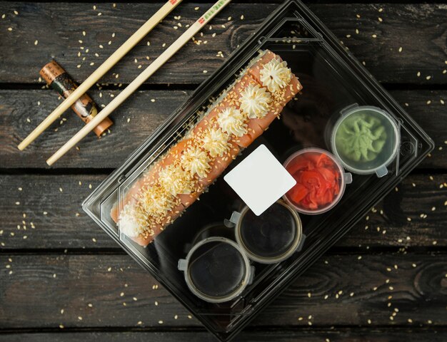 scatola di plastica di rotoli di shushi per la consegna con salmone, salse, wasabi e zenzero