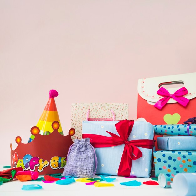 Scatole presenti con corone; palloncini e borse per la spesa su sfondo rosa
