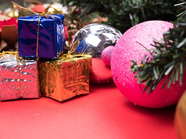 Scatole regalo di Natale avvolte in diversi colori sotto l'albero di Natale su sfondo rosso. . Decorazione interna festiva.