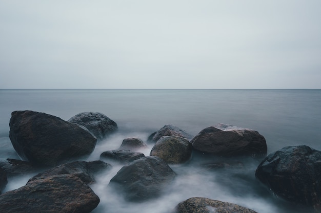 Scatto ipnotizzante di una spiaggia rocciosa sotto un cielo nuvoloso a Ostsee, Germany