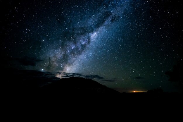 Scatto mozzafiato delle sagome delle colline sotto un cielo stellato nella notte