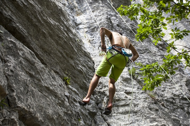 Scatto mozzafiato di un giovane maschio che si arrampica sull'alta roccia a Champfromier, Francia