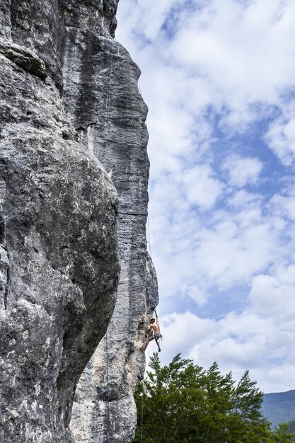 Scatto mozzafiato di un giovane maschio che si arrampica sull'alta roccia a Champfromier, Francia