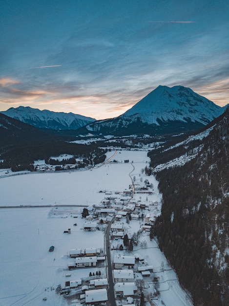 Scatto mozzafiato di una catena montuosa con una città sotto di essa in inverno