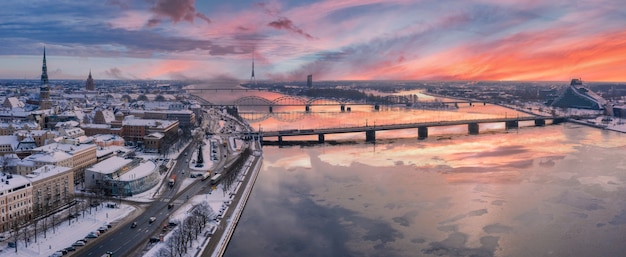 Scatto panoramico del bellissimo tramonto sulla città di Riga coperta di neve con il fiume Daugava e il centro cittadino