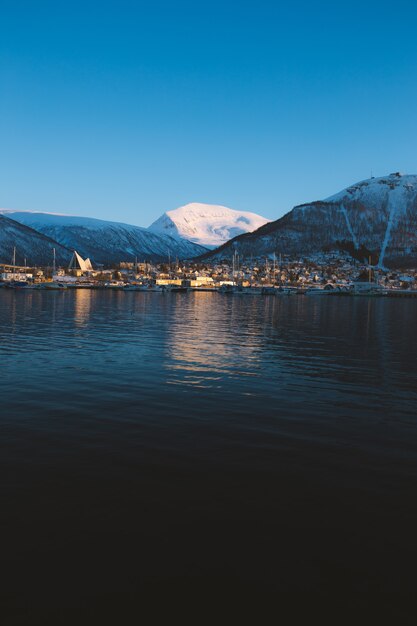 Scatto verticale di un lago circondato da montagne innevate a Tromso, Norvegia