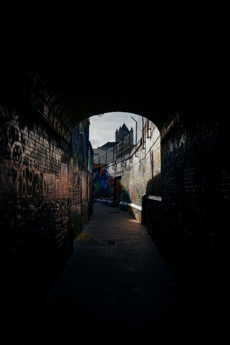 Foto gratuito scatto verticale di un sentiero al centro di muri di mattoni con graffiti su di loro