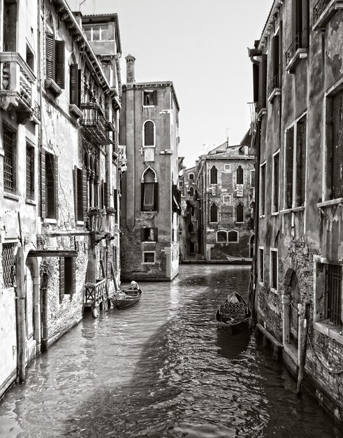Scatto verticale in scala di grigi di un canale nel quartiere storico di Venezia, Italia