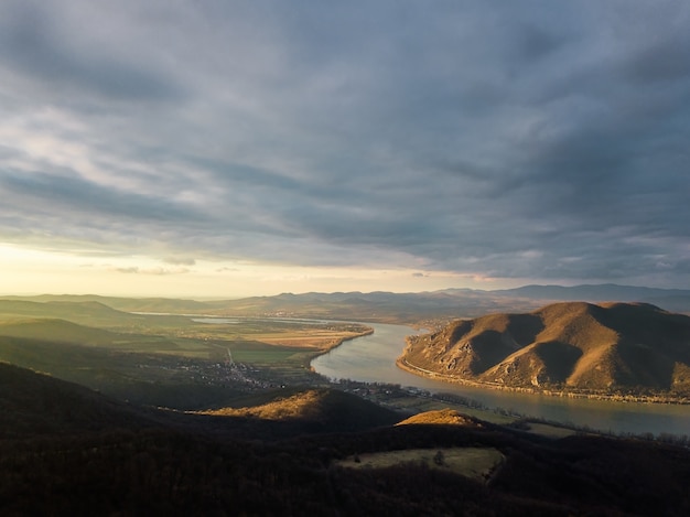 Scena affascinante di un fiume tra foresta e collina sotto il cielo nuvoloso