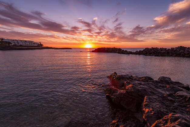 Scenario mozzafiato dello splendido tramonto e del colorato cielo nuvoloso riflesso nel mare