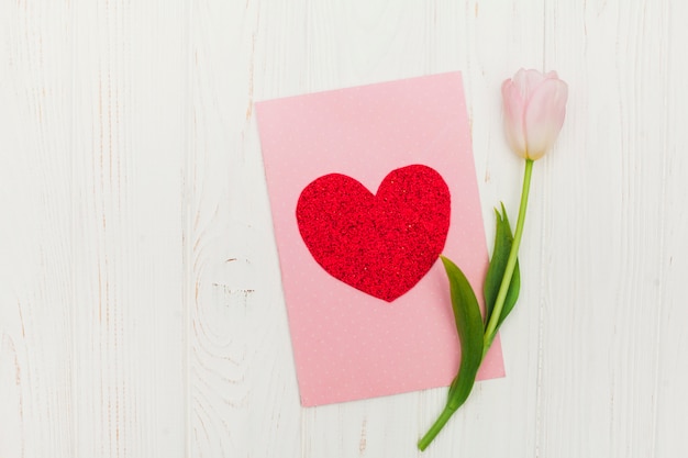 Scheda del biglietto di S. Valentino con il fiore sulla tabella di legno bianca