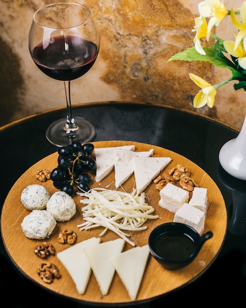 Scheda di formaggio con un bicchiere di vino rosso.