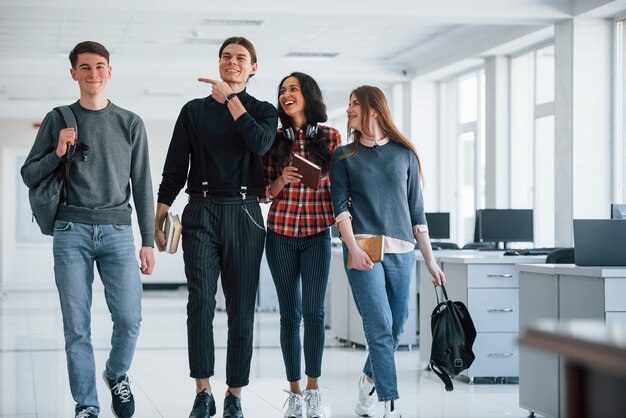 Scherzando. Gruppo di giovani che camminano in ufficio durante la pausa