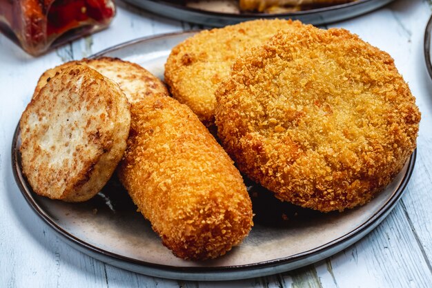 Schnintzel di pollo vista laterale con strisce di pollo fritto nel grasso bollente e tortino su un piatto