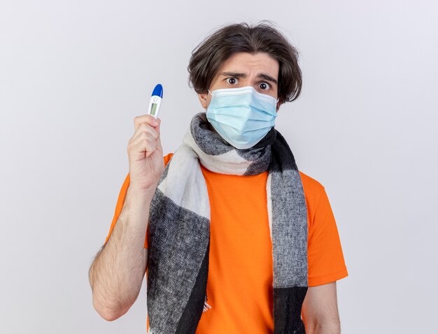 Sciarpa da portare del giovane uomo ammalato confuso e termometro della tenuta della mascherina medica isolato su fondo bianco
