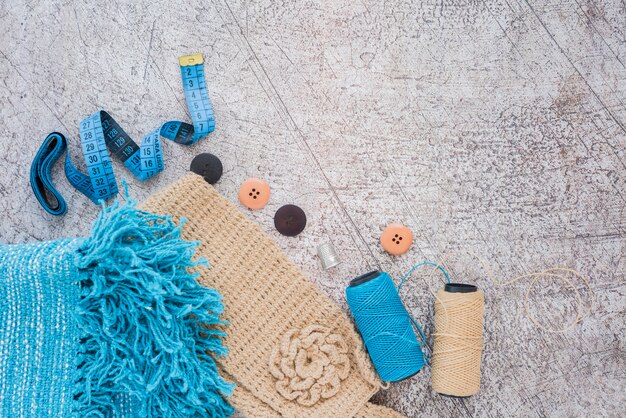 Sciarpa lavorata a maglia; nastro di misurazione; pulsante; bobine su sfondo con texture