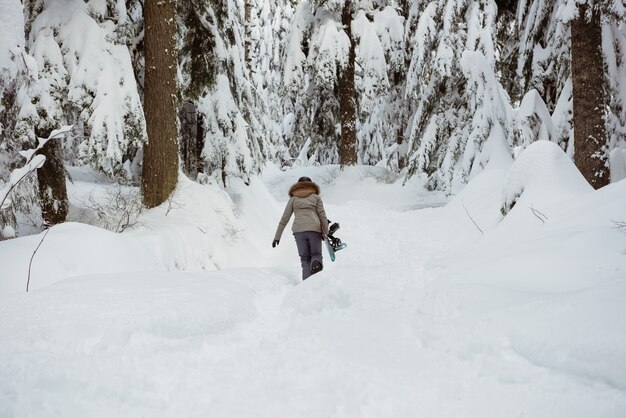 Sciatore femminile che cammina con gli sci sul paesaggio innevato