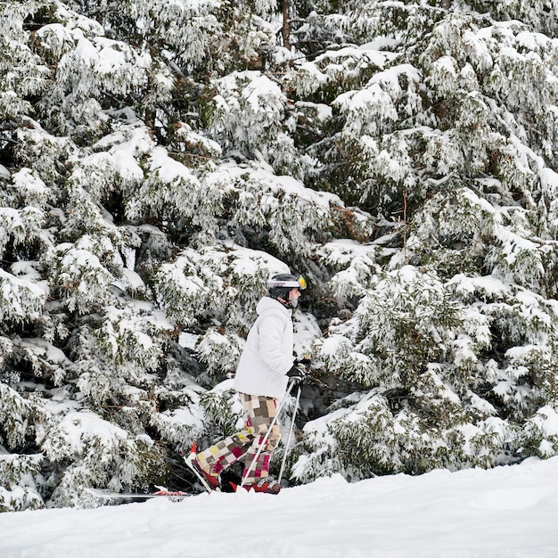Sciatore maschio che cammina attraverso la neve nella foresta di inverno