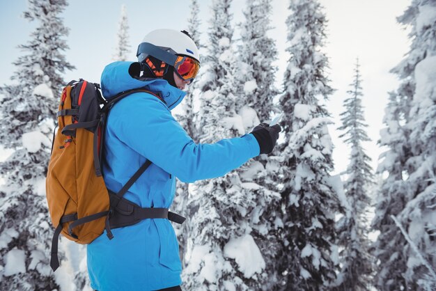 Sciatore utilizzando il telefono cellulare sulle montagne innevate
