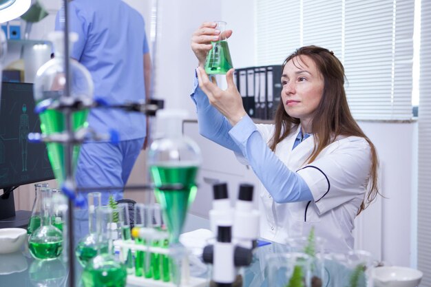 Scienziata matura che fa test scientifico nel suo laboratorio di ricerca. Provette chimiche.