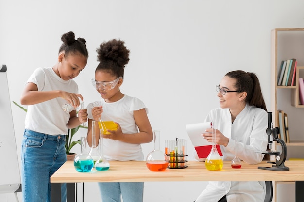 Scienziata osservando le ragazze sperimentando chimica